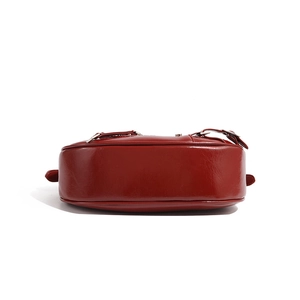 Detailed bottom view of deep red leather shoulder bag with smooth semi-circular base design