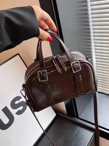 Detail of dark brown Boston handbag with dual handles and silver buckle accents