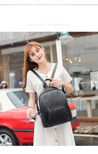 Outdoor model shot of a stylish black faux leather backpack with front zipper detail