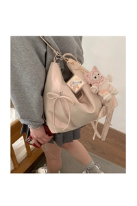 Detailed shot of pink faux leather bag with bow accent and plush charm accessory