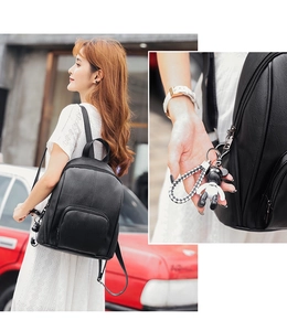 Detail of black soft leather backpack with textured finish and trendy bear charm pendant