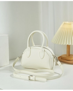 Close-up of minimalist cream white Boston handbag with silver hardware and smooth texture