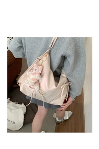 Detail of beige glossy leather shoulder bag with bow drawstring and a plush toy charm