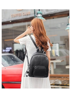 Detail of a black leather backpack for women with a cute panda charm in a street setting