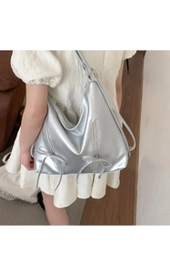 Detail of silver metallic leather tote bag with bow accent and vertical zipper on model