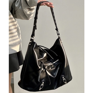 Detail of black glossy leather hobo bag with silver studs and buckles on a model