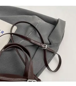 Detail of dark brown leather adjustable strap with silver buckle and fine stitching