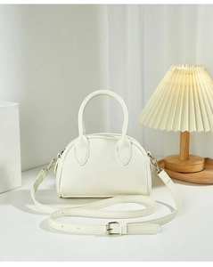 Detail of a minimalist cream Boston bag with dual handles and adjustable strap in a soft set