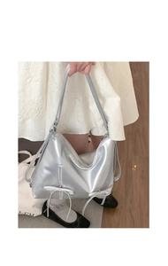 Close-up of metallic silver tote bag featuring decorative bows and dual zippers