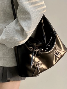 Detail of black leather tote bag featuring silver rivets and motorcycle style hardware