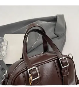 Close-up of dark brown vintage handbag featuring oil-wax leather texture and silver hardware