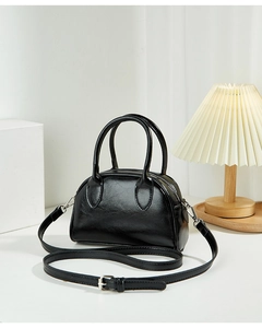 Detail of a black glossy leather Boston bag with adjustable shoulder strap and dual handles