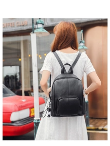 Detail of a chic black soft leather women's backpack with a cute panda pendant on side