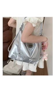 Detailed view of silver metallic hobo bag with bow accents and vertical zippers