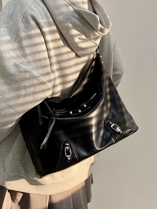 Detail of black glossy leather tote bag with vintage studs and bohemian tassels strap
