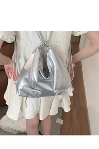 Silver metallic bow backpack with adjustable straps and zipper details shown on model