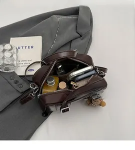 Spacious interior of dark brown leather crossbody bag with dual zippers and items