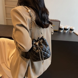 Close-up of quilted leather bucket bag with gold-tone chain strap and drawstring detail