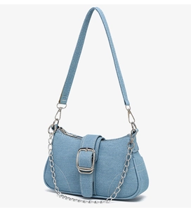 Détail d'un sac sous les bras en denim bleu clair avec boucle argentée et chaîne en métal