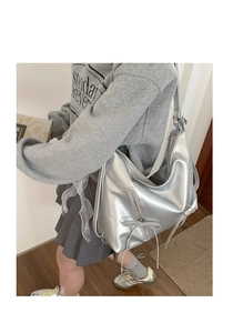 Close-up of stylish silver backpack with ribbon bow and multi-zipper pocket detail