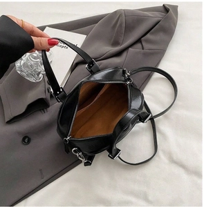 Top view of small black patent leather handbag showing tan lining and inner pocket detail