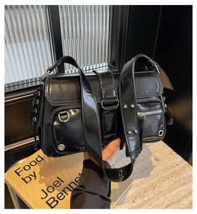 Detail of black glossy Y2K bag with multiple zippers and silver metal D-rings