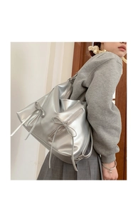 Detail view of silver metallic tote bag with double zipper and stylish ribbon accents
