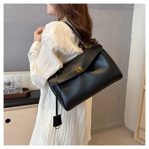 Model wearing a minimalist black leather tote bag with gold hardware for a modern casual style