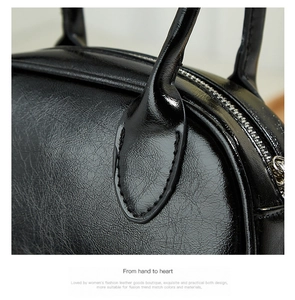 Detail of black glossy leather Boston bag showing stitching and lychee grain texture
