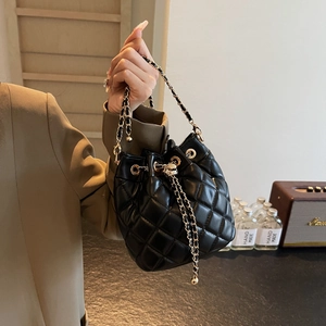 Detailed close-up of black quilted bucket bag with gold chain and drawstring closure