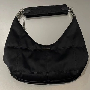Close-up of black nylon hobo bag featuring a sleek silver metal bar and wide shoulder strap