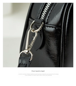 Close-up of silver-tone hardware and glossy black leather on a Boston handbag