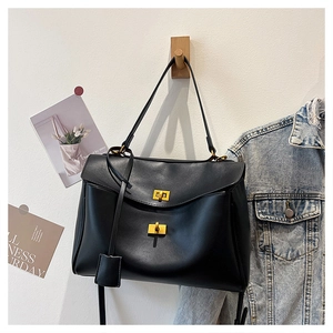 Vue détaillée du cabas en cuir noir avec boucles à fermoir tournant dorées et bandoulière