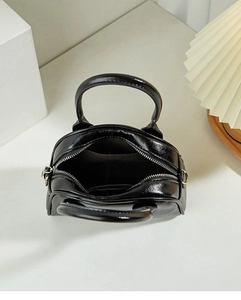 Top view of black glossy Boston bag interior with main compartment and zipper pocket