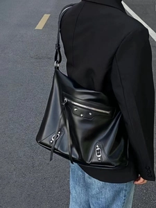 Close-up of black matte leather tote bag with silver studs and tassel zipper detail