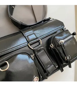 Close-up of black glossy leather shoulder bag featuring silver rings and white stitching
