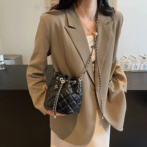 Detail of black quilted bucket bag featuring gold chain strap and drawstring closure