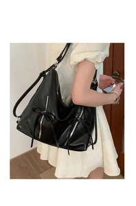 Detail of black glossy hobo bag with silver zippers and stylish bow knot accents