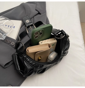 Internal storage detail of black pleated cloud bag with phone and wallet inside