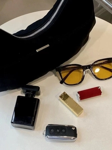 Detailed top view of black crescent shoulder bag with sunglasses and personal items