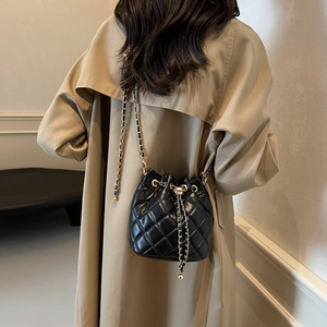 Detailed view of black quilted bucket bag featuring drawstring and gold chain strap