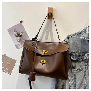 Détail du sac cabas en cuir marron foncé avec fermoirs dorés et bandoulière ajustable