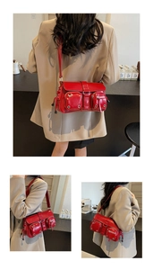 Detail of red punk baguette bag showing metallic eyelets and multi-pocket design features