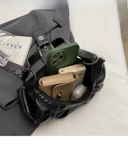Spacious interior of black pleated leather handbag showing phone and wallet storage