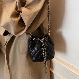 Detail of quilted leather bucket bag featuring gold skull drawstring closure and chain strap