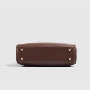 Vue détaillée du fond du sac en cuir marron avec quatre pieds de protection dorés