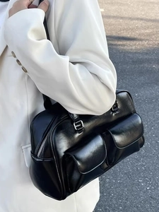 Detail of black faux leather shoulder bag with silver zipper and utility pockets