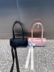 Detail of pink and black underarm bags featuring decorative satin ribbon bow accents