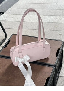 Detail of light pink shoulder bag with large white satin bow and metal zipper closure