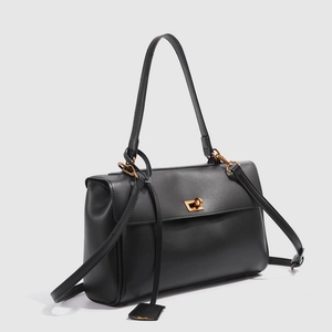 Détails d'un sac cabas en cuir noir avec fermoir rotatif en métal doré chic